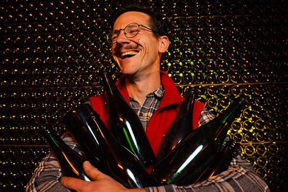 Vigneron riant, les bras chargés de bouteilles de champagne