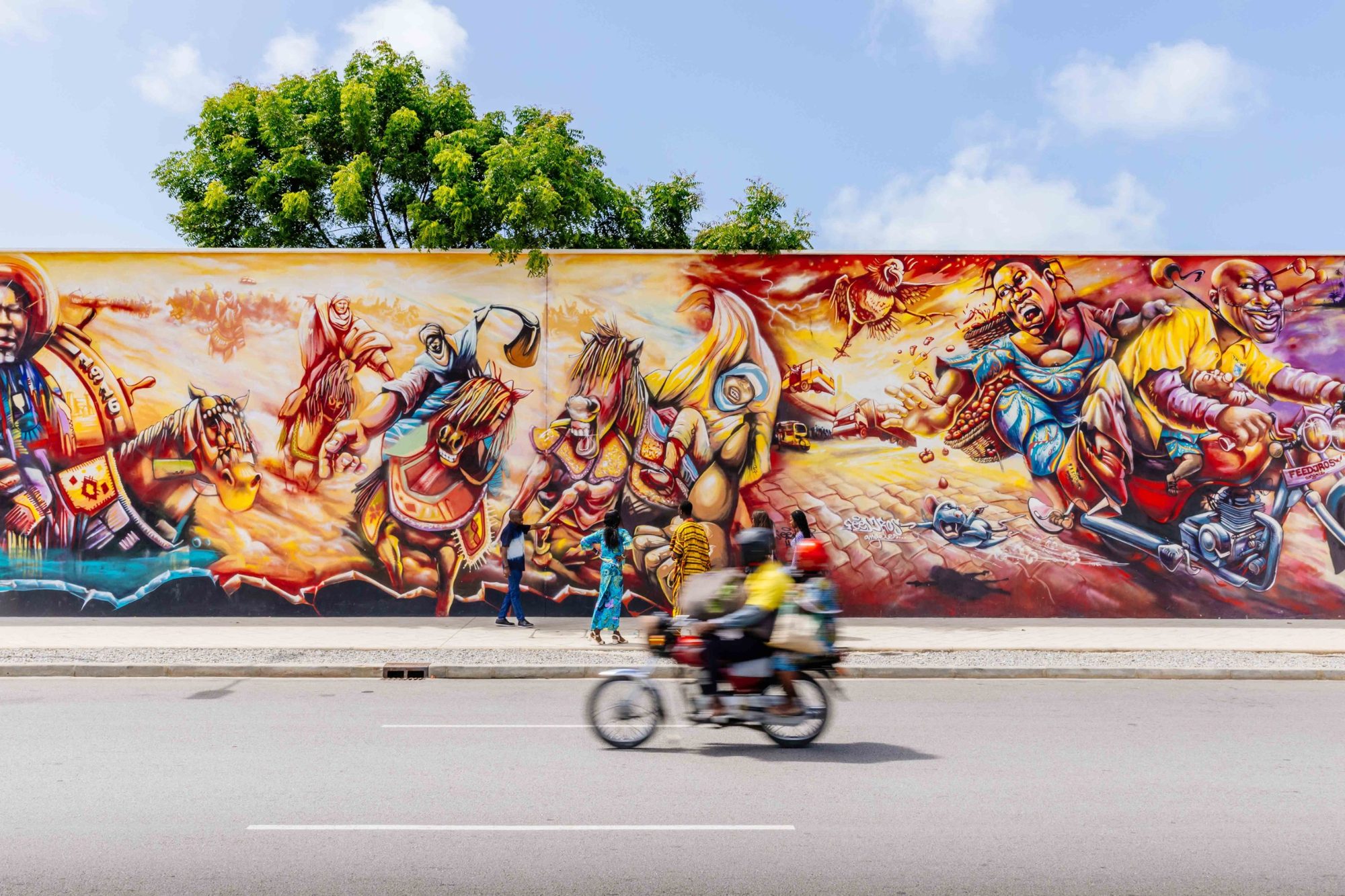 Fresque murale colorée à Cotonou, une moto passe au premier plan