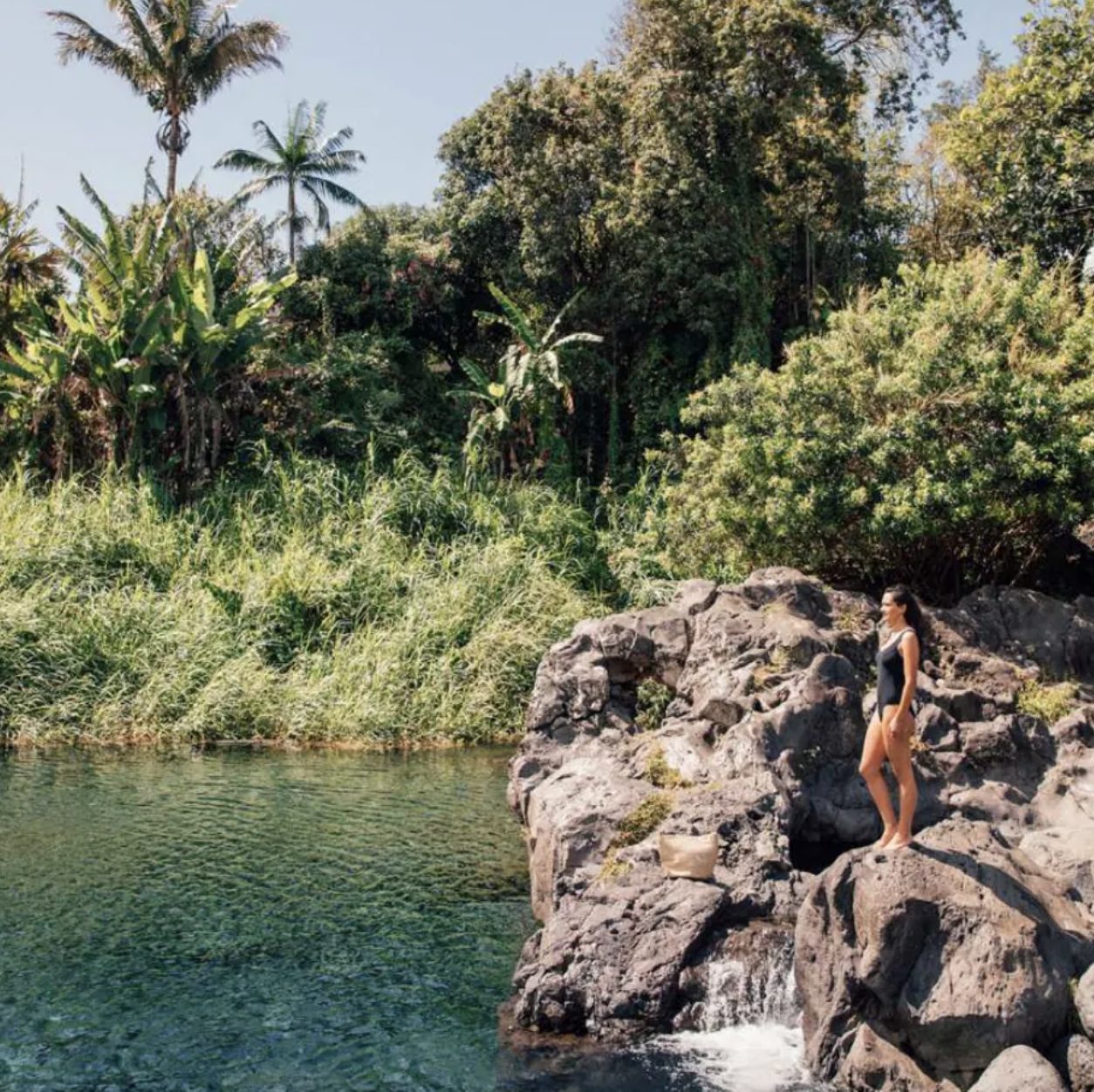 Baigneuse sur un rocher au bord d’un bassin à La Réunion